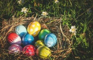 Bunte Ostereier in einem Heu-Nest auf der Wiese