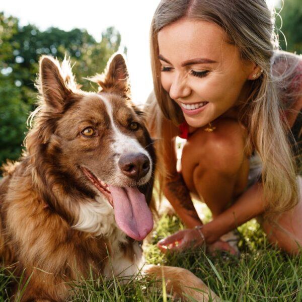 Frau mit Hund sitzt auf gedüngtem Rasen