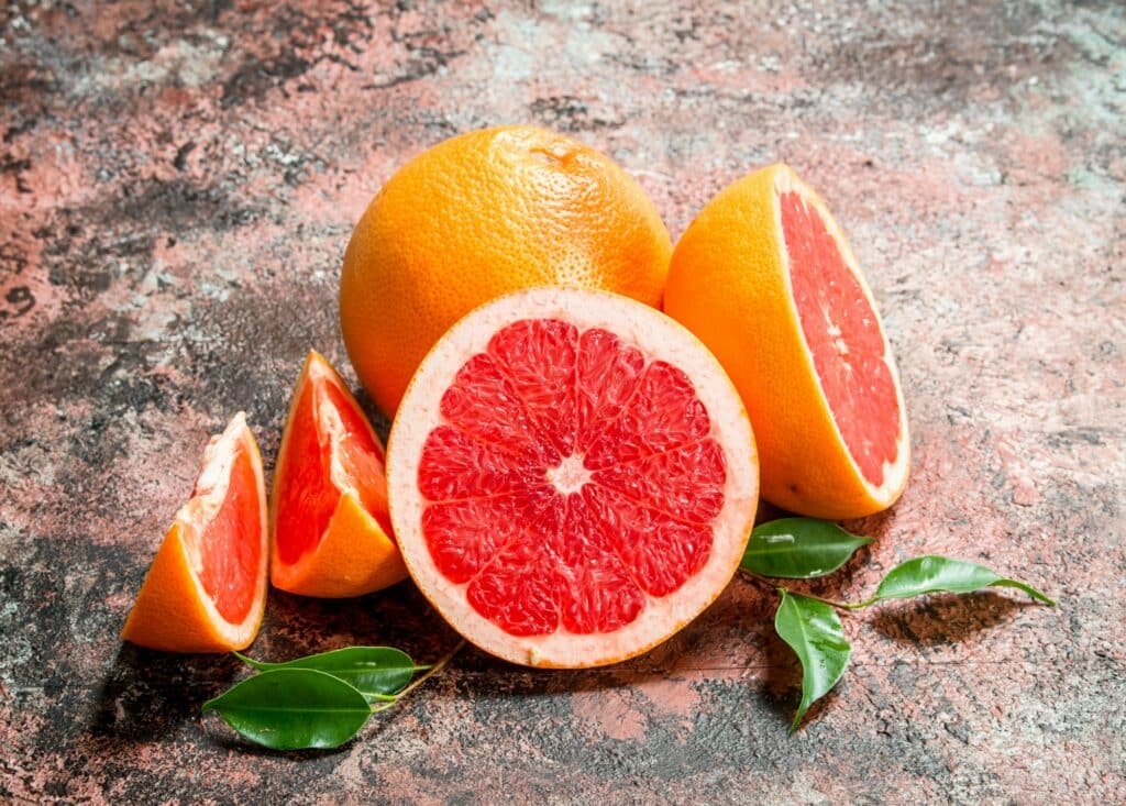 Grapefruit – in Hälften und Viertel geschnitten mit Blättern ringsum