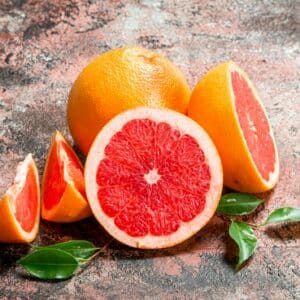 Grapefruit – in Hälften und Viertel geschnitten mit Blättern ringsum