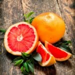 Ganze und aufgeschnittene rosa Grapefruit auf einem Holztisch