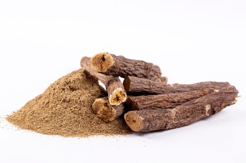 Süßholz und Süßholzpulver auf weißem Hintergrund