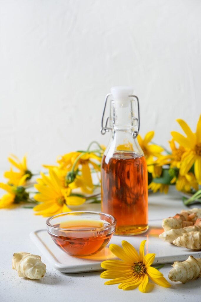 Sirup aus Topinambur in der Flasche, ergänzt mit Blüten und Knollen