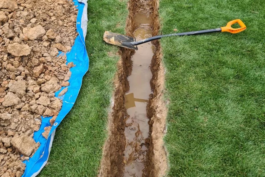Graben für ein Drainagerohr im Rasen